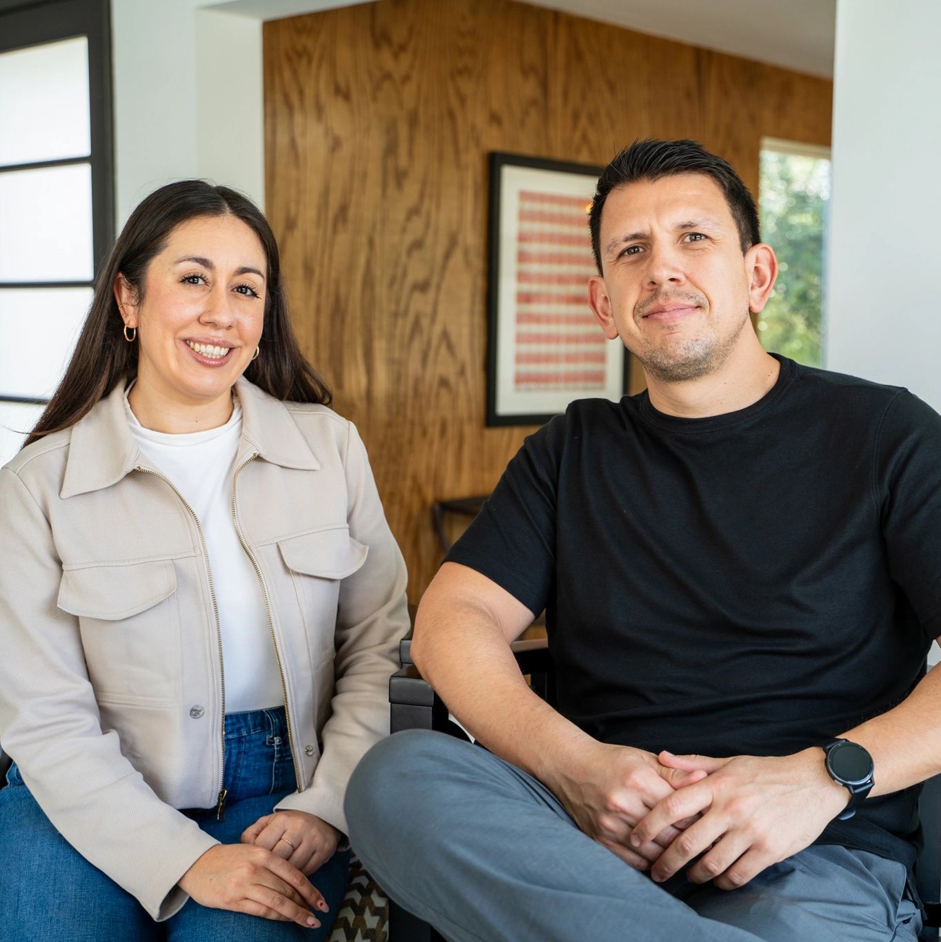 Smiling man and woman sitting indoors.