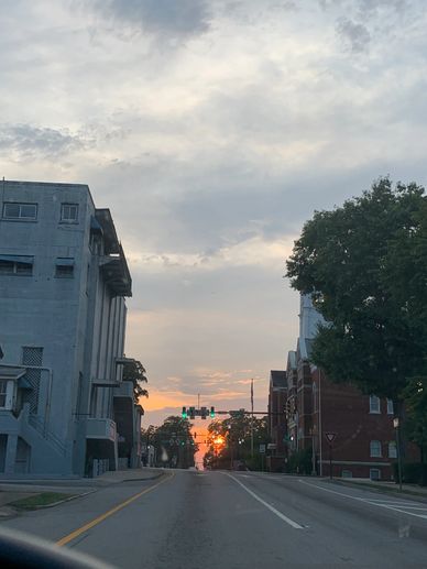 Sunset view down an urban street with buildings and trees.