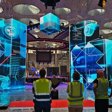 Four workers observe a futuristic digital display with car and innovation themes.