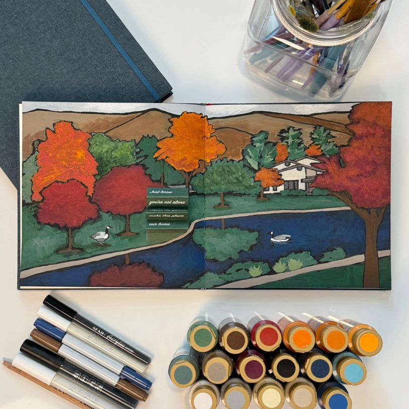 Colorful autumn landscape painting with trees, a river, and ducks, surrounded by art supplies.