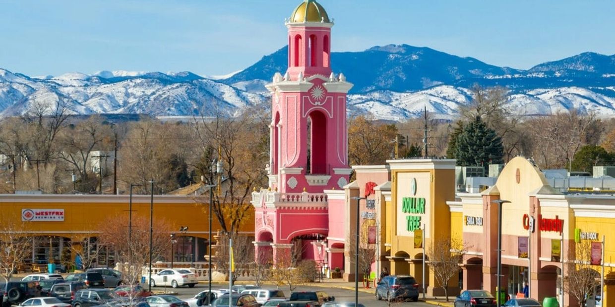 Shopping center with a pink tower and snowy mountains in the background.