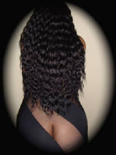 Woman with long curly hair posing with back exposed in black outfit.
