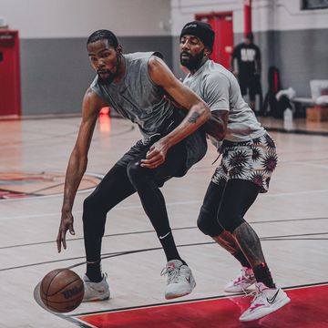 Two men playing basketball indoors with one guarding the other.