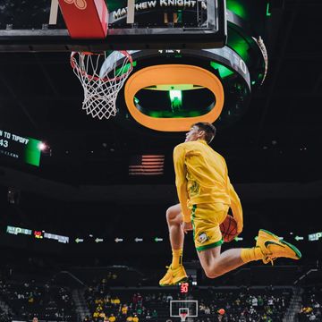 Basketball player in yellow mid-air dunking during a game.