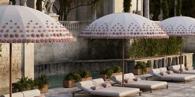 Elegant poolside lounge chairs with large umbrellas and soft cushions.
