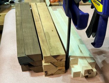 Three sets of wooden beams with dovetail joints clamped in place on a workbench.