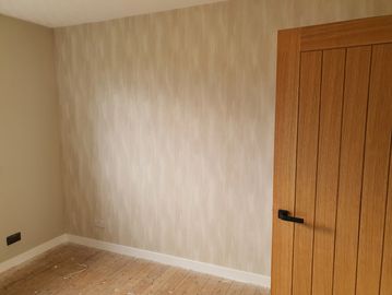 Empty room with patterned wall and wooden door.