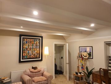 Cozy living room with framed artworks and a cat on an armchair.