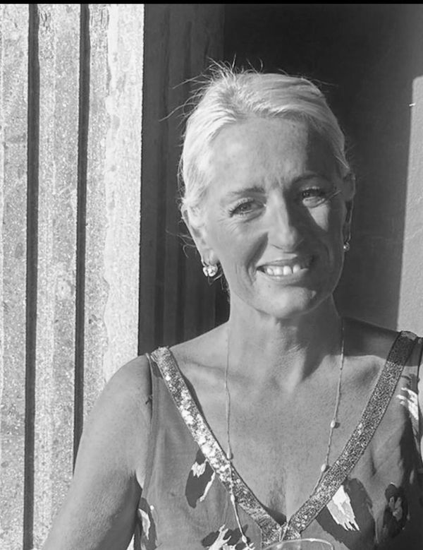 Smiling woman in sunlight with patterned dress.