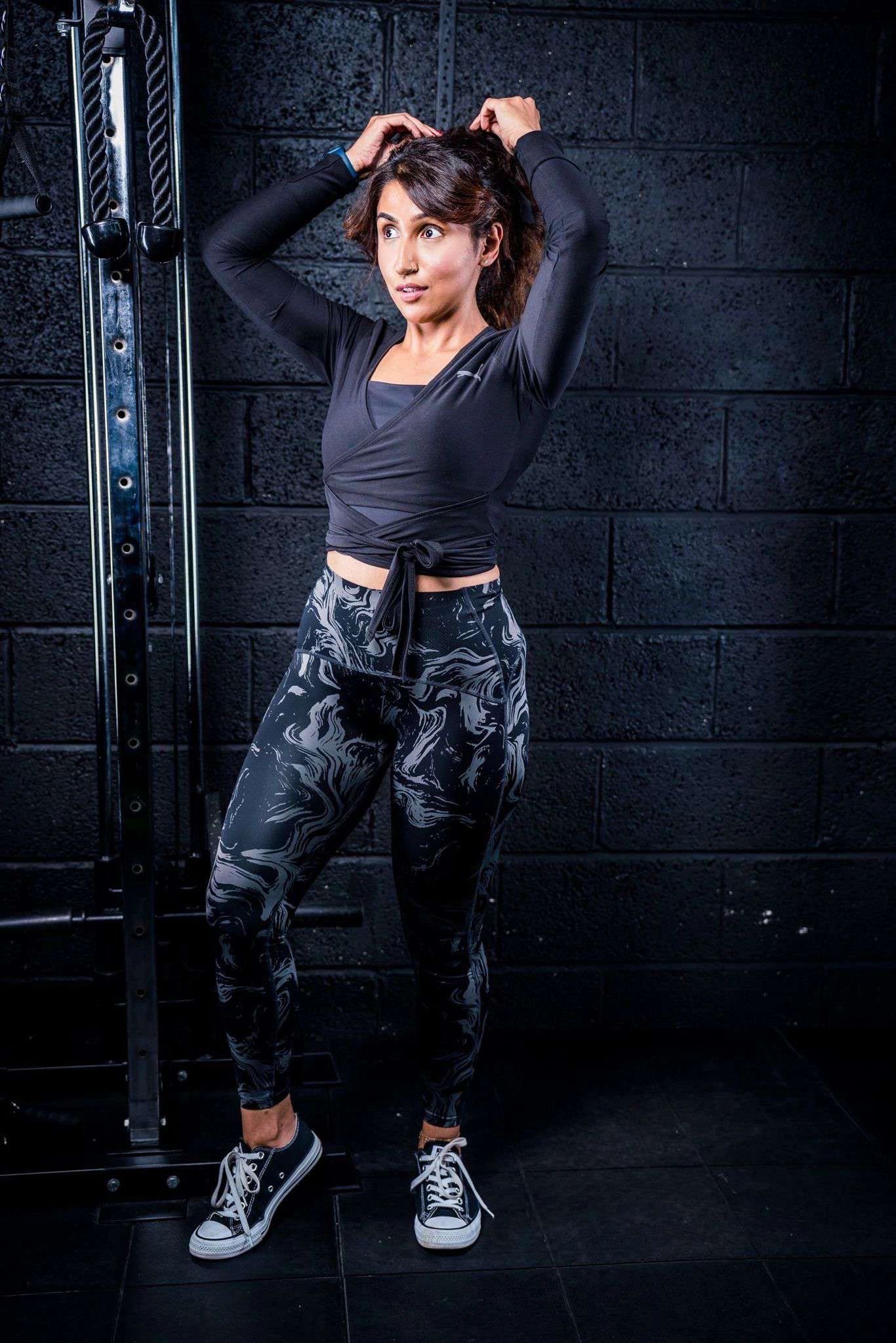 Woman in athletic wear tying her hair in a gym.