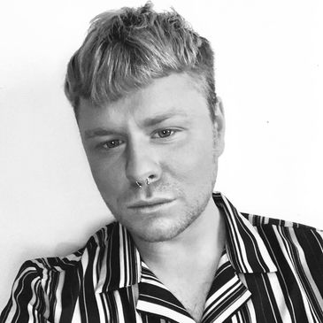 young man with short grey hair with short fringe and stripped shirt