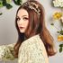 girl sat on chair in wedding dress with brown curled hair and floral hairband with flower background