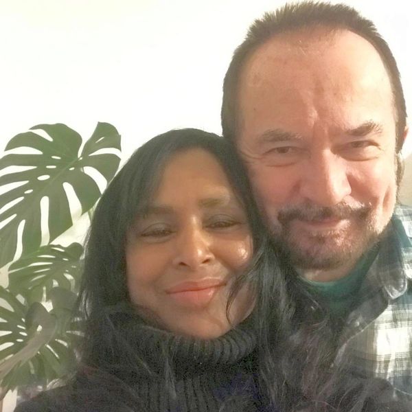 Happy couple posing for a selfie indoors with a plant in the background.