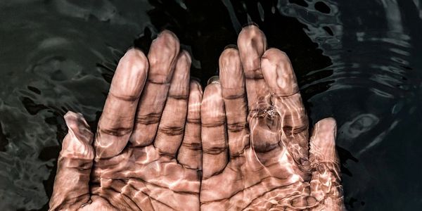 Hands cupped under water with light reflections.
