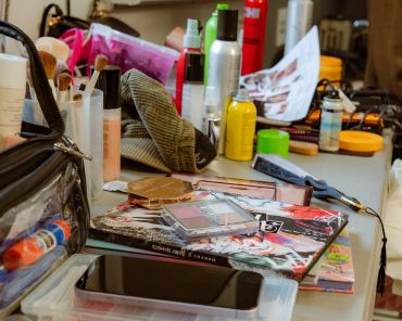 A cluttered table with cosmetics and personal items.