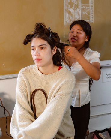 Woman styling another woman's hair indoors.