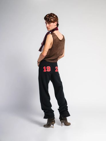 Fashion model poses in trendy outfit with a scarf and heeled boots.