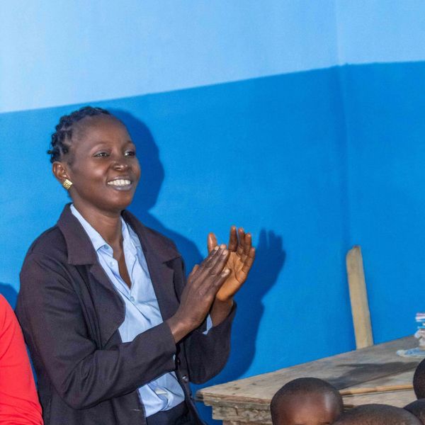 Woman clapping and smiling indoors.