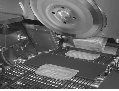 Black and white image of industrial dough rolling machine.
