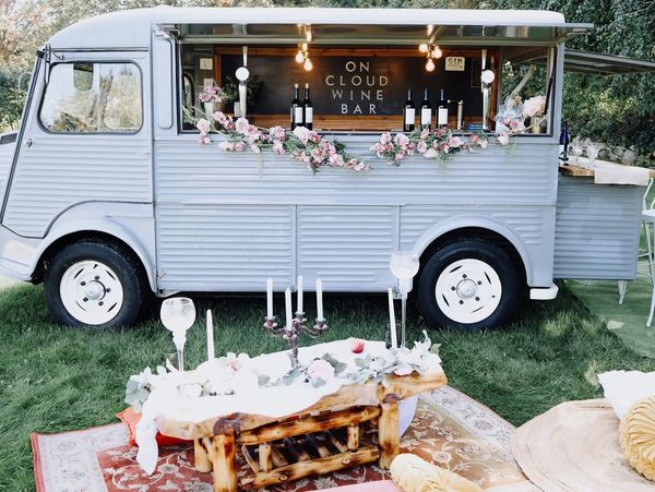 Vintage wine bar truck decorated with flowers and cozy seating area outdoors.