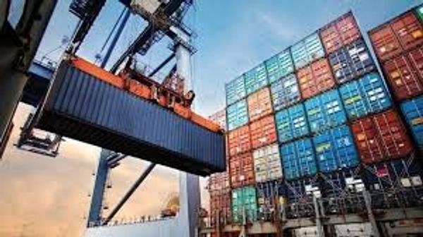 A crane lifts a shipping container at a busy port with stacked containers.