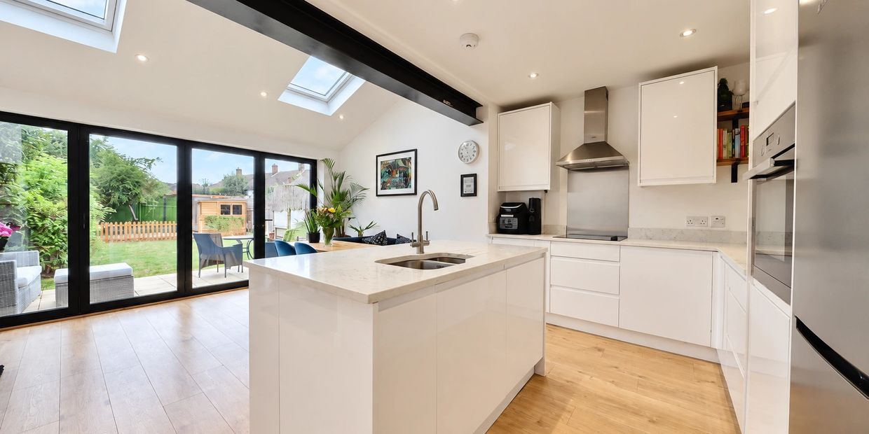 Modern white kitchen with island and garden view.