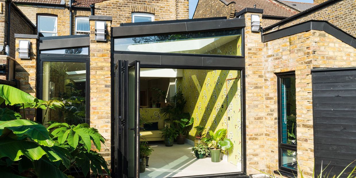 Newham wraparound extension with reclaimed brickwork, black glazing and open bi-fold doors.