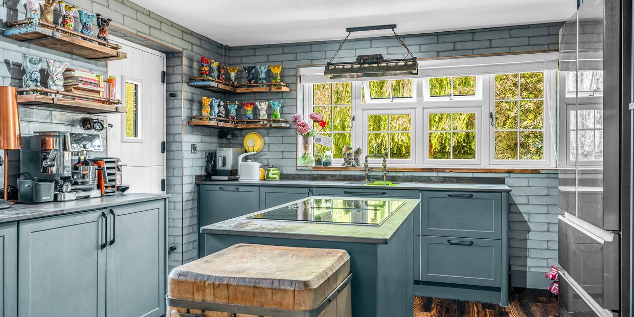 Cottage kitchen with painted cabinetry, an island, timber shelves and a butcher’s block.