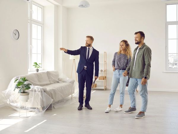 Real estate agent giving potential buyers or future tenants tour about big new house