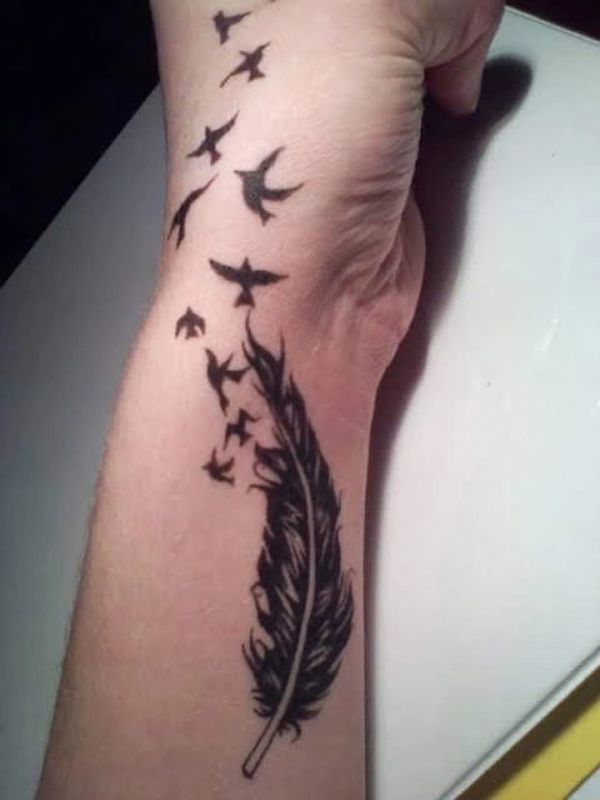 Lightweight feather with birds flying from tip tattoo along forearm