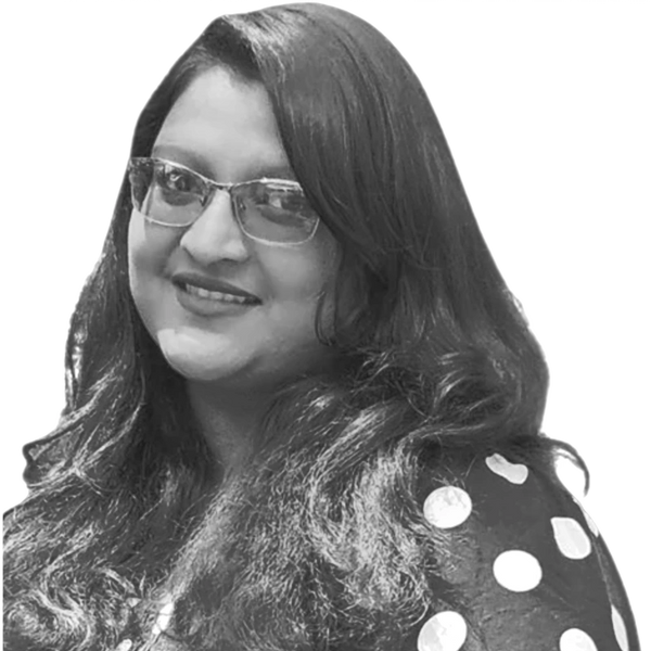 Smiling woman with glasses and long hair in polka dot attire.