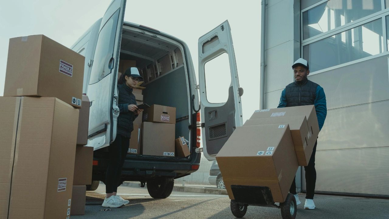 Workers loading fragile packages into a delivery van outdoors.