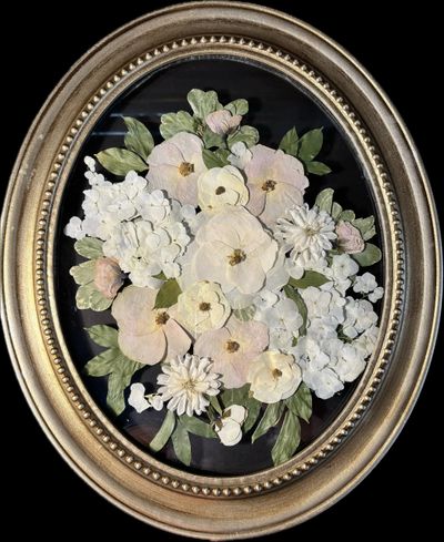 Oval frame with delicate pressed flowers art in soft pastels.