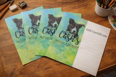 Gift certificates for custom dog sketch portraits on a wooden desk.