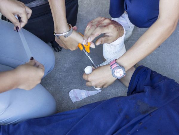 People providing first aid to an injured hand.
