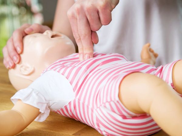 Person performing infant CPR on a doll.