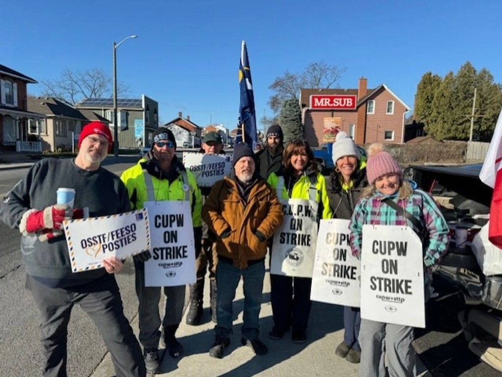 Group of people holding strike signs on a sunny day.