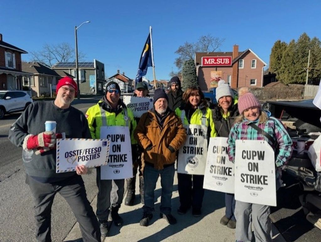 Group of people holding strike signs on a sunny day.