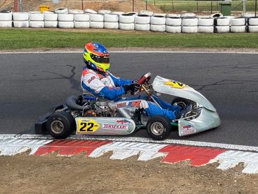 Go-kart racer in full gear navigating a track corner.