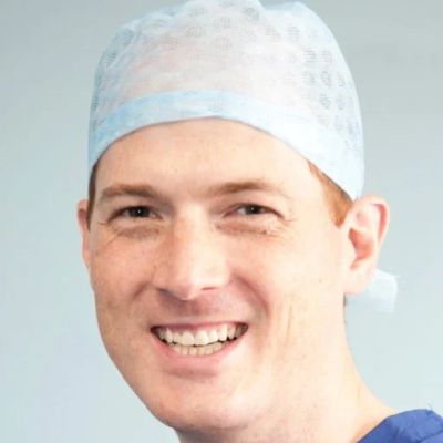 Smiling medical professional wearing a surgical cap and scrubs.