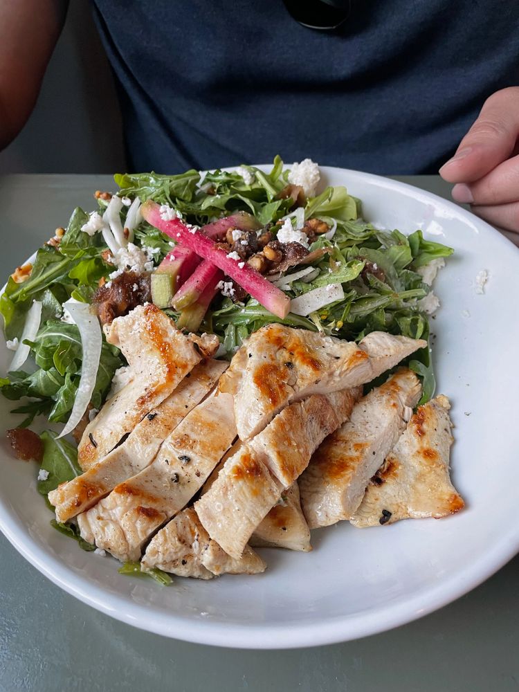 Grilled chicken salad with mixed greens and radish sticks.