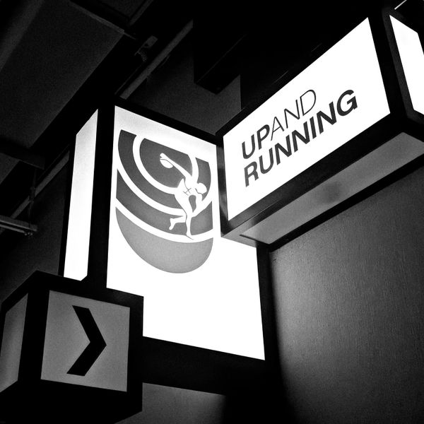 Black and white signs with a runner and the text 'UP AND RUNNING'.