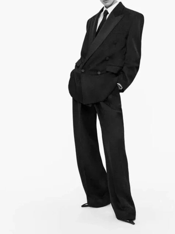 Person in an oversized black suit with wide-legged pants and a tie.