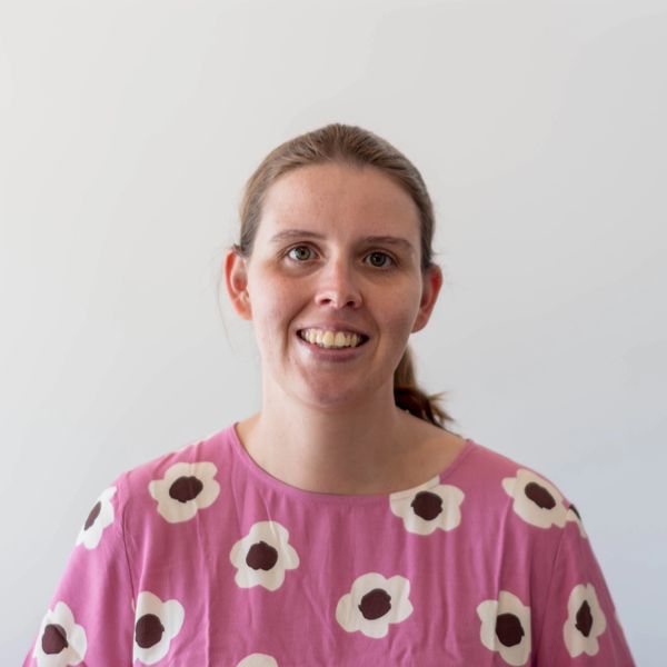 Smiling woman in a pink floral shirt.