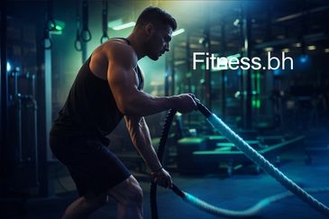 Muscular man doing battle rope workout in gym with intense focus.
