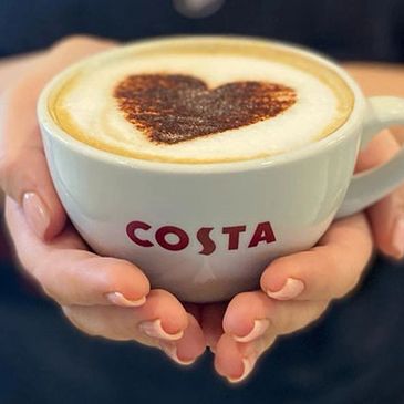 Hands holding a Costa coffee cup with a heart-shaped foam design.