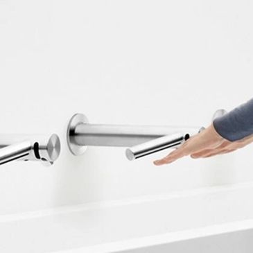 Person using a modern touchless faucet in a minimalist bathroom.