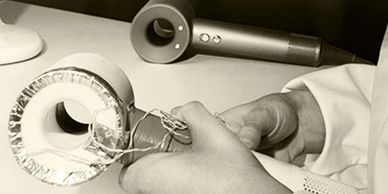 Hands assembling a prototype device resembling a modern hair dryer.
