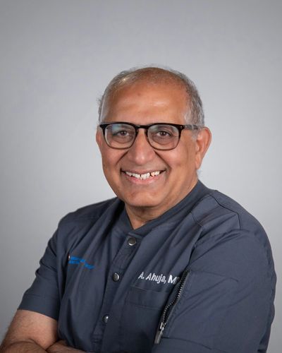 Smiling middle-aged man in glasses and medical scrubs.