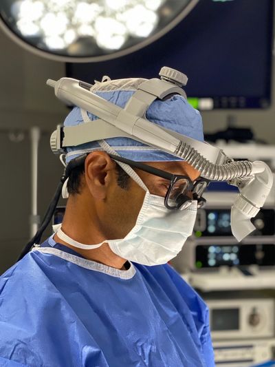 Surgeon in blue scrubs and mask focusing during surgery.